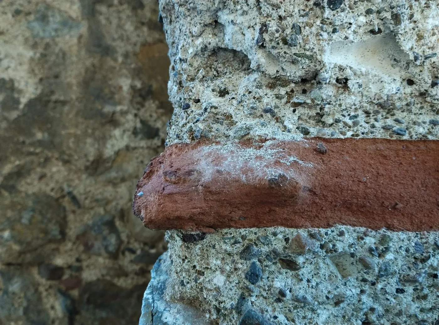 Detail zvětralého betonu a cihlového pásu