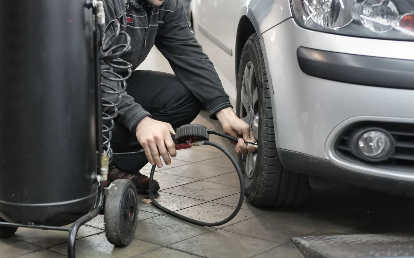 Mechanik kontroluje tlak pneumatiky kompresorem