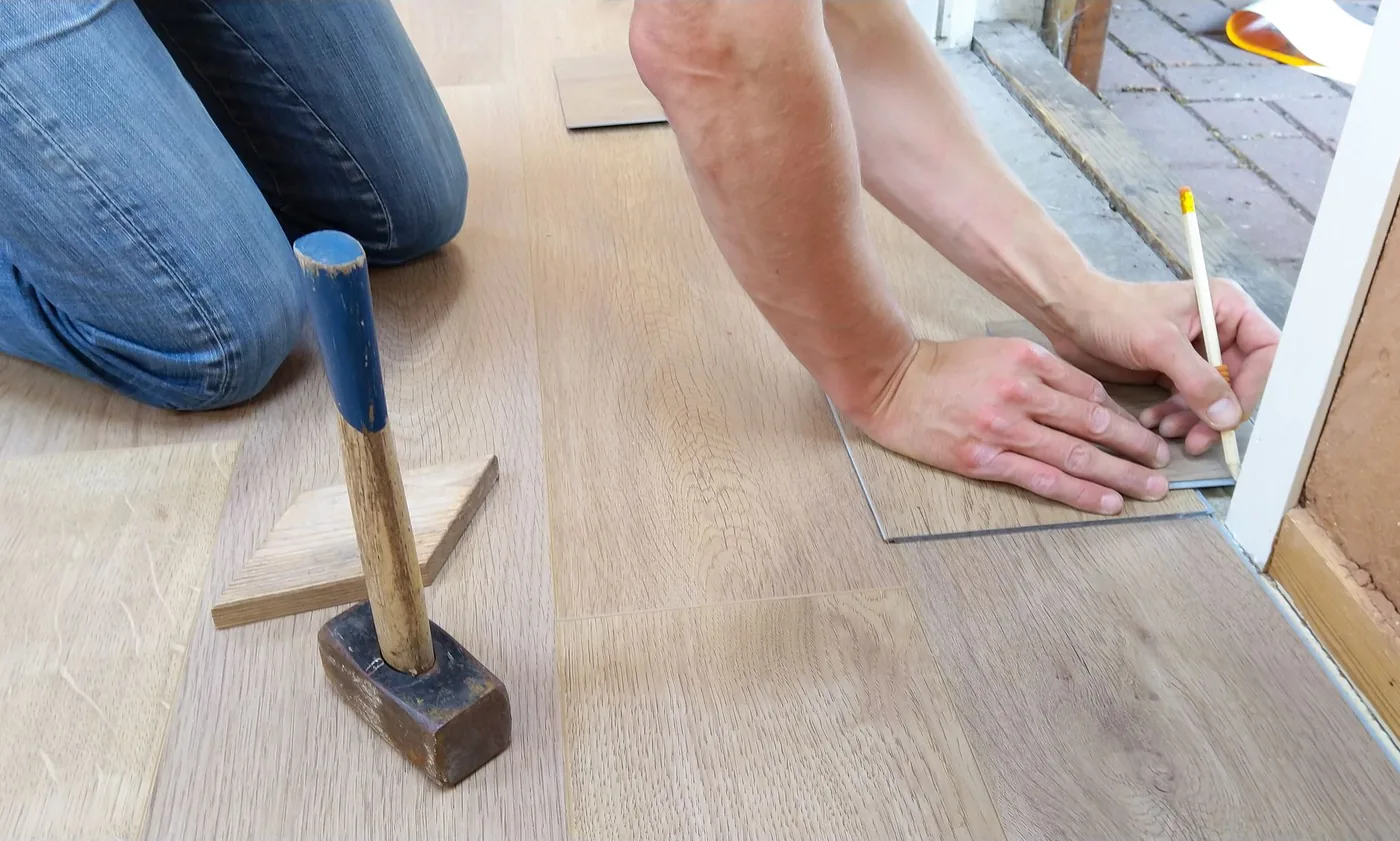 Řemeslník pečlivě měří podlahové panely