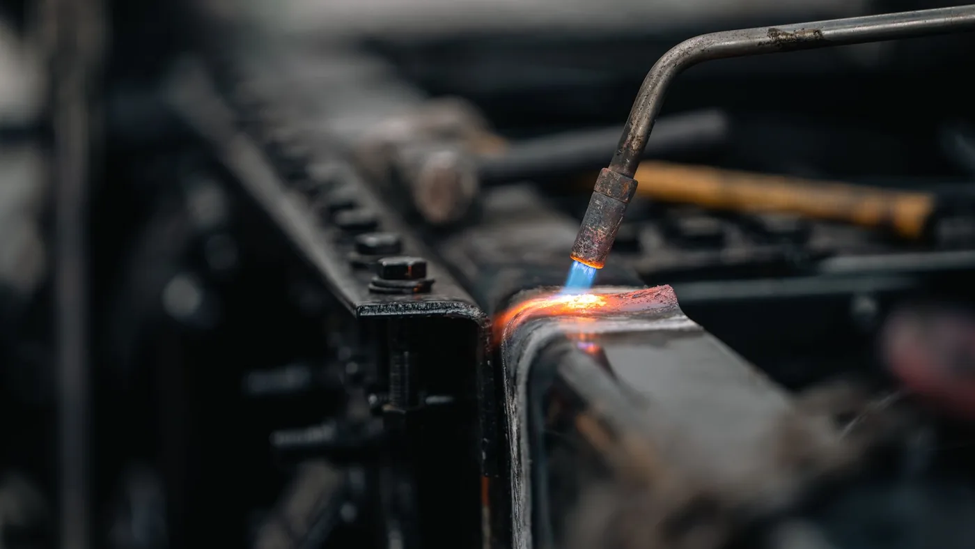 Detail svařovacího hořáku s modrým plamenem na kovu